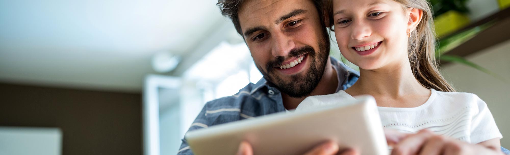 Vater und Tochter schauen sich auf einem Tablet die Informationen über die Produkte der Stadtwerke Prenzlau an